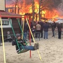 miniature pour Un garçon fait de la balançoire à côté d'une maison qui brûle