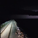 Des éclairs vus depuis un train de nuit qui traverse un lac